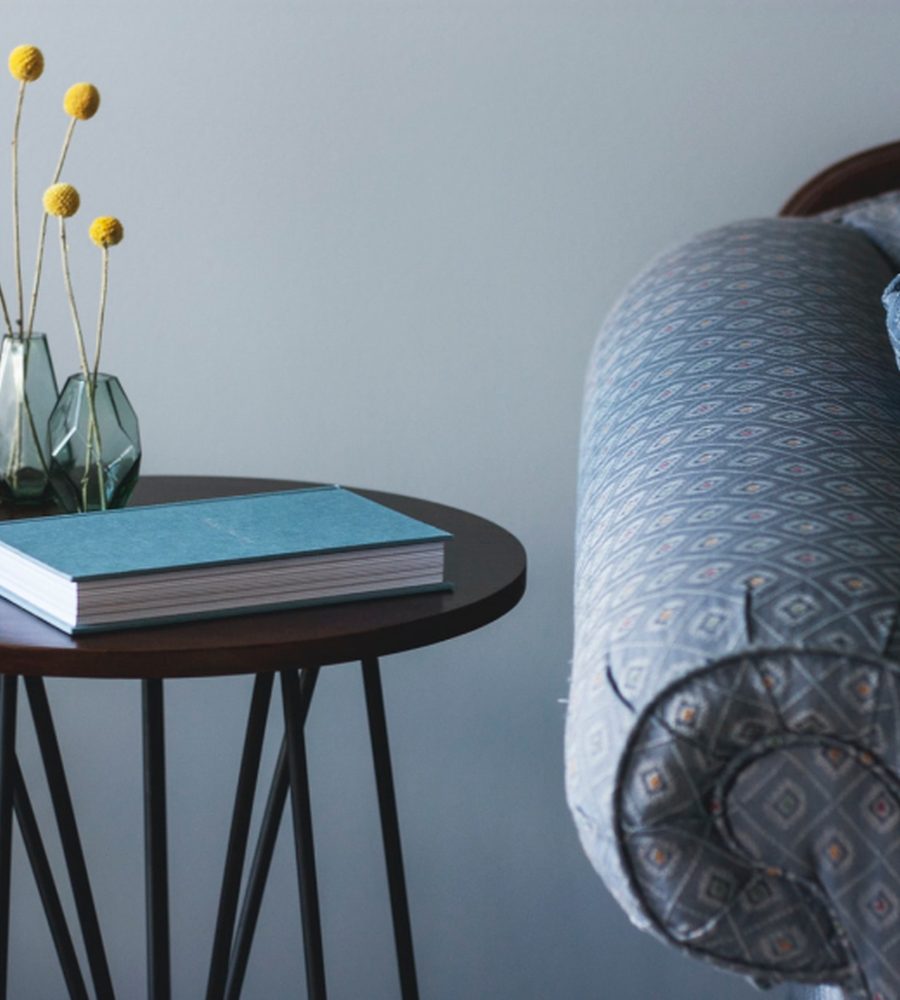 A blue armchair beside a small table with books and flowers